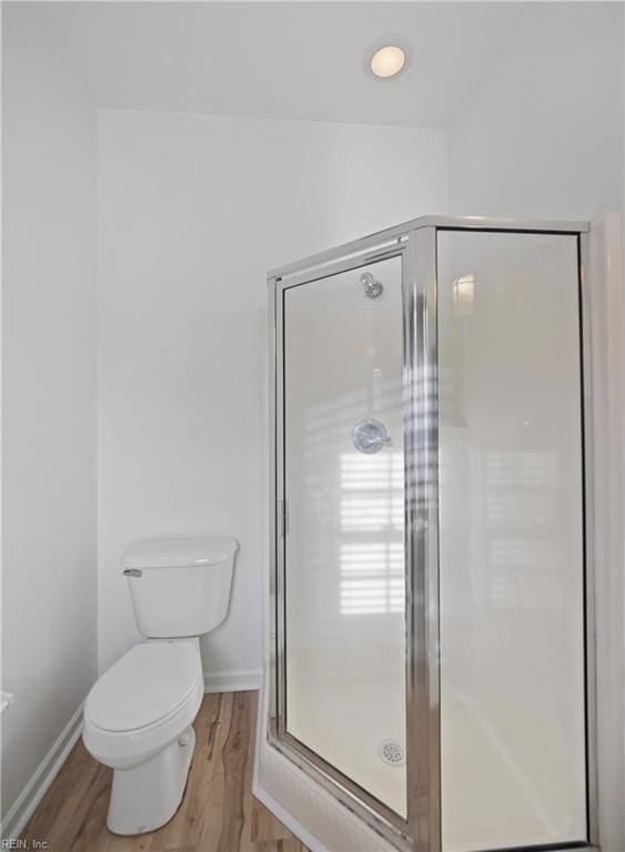 bathroom with baseboards, a shower stall, toilet, and wood finished floors