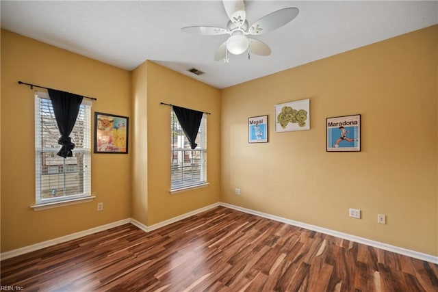 unfurnished room with a ceiling fan, visible vents, baseboards, and wood finished floors