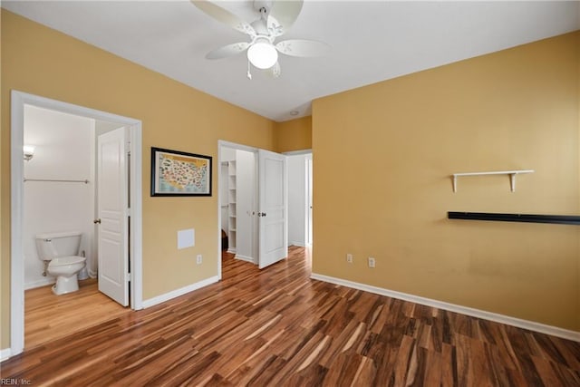 unfurnished bedroom with ensuite bathroom, wood finished floors, a ceiling fan, and baseboards