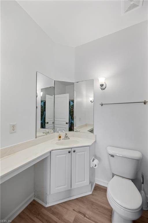 full bath with toilet, visible vents, wood finished floors, and vanity