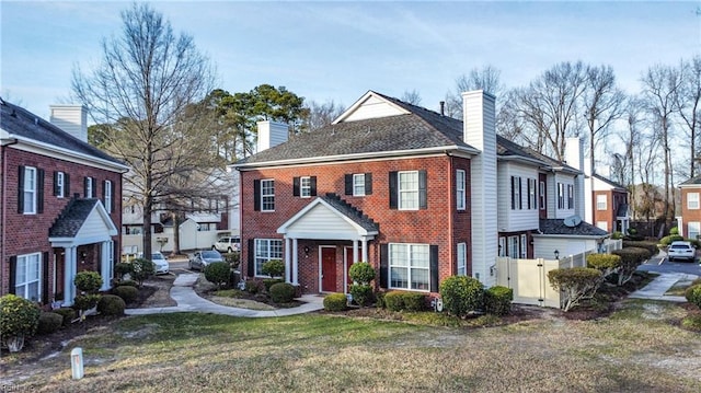 view of front of property with a chimney, a front lawn, and brick siding