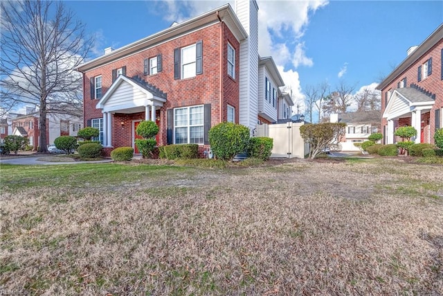 view of front of house with brick siding, fence, a gate, a chimney, and a front yard