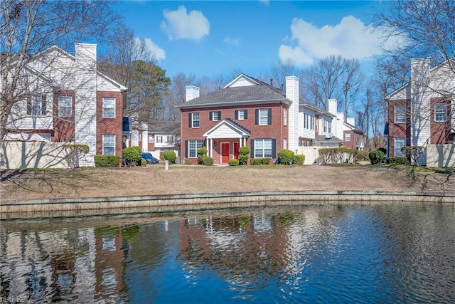 back of property featuring brick siding, a water view, and a chimney