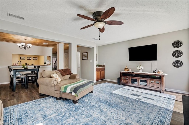 living room featuring baseboards, visible vents, dark wood finished floors, and a textured ceiling