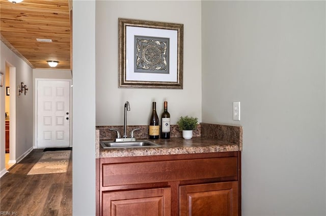 bar with baseboards, dark wood finished floors, wooden ceiling, a sink, and indoor wet bar