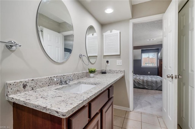 ensuite bathroom with tile patterned flooring, connected bathroom, vanity, and baseboards