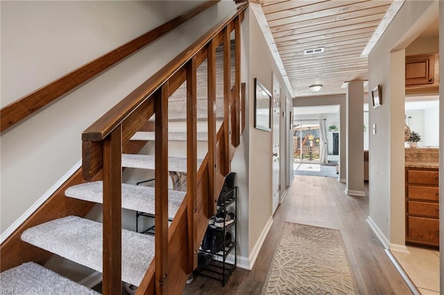 staircase with wood ceiling, baseboards, and wood finished floors