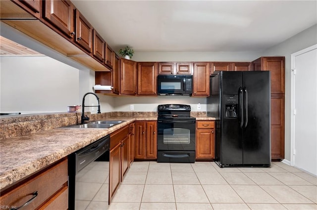 kitchen with brown cabinets, a sink, black appliances, and light tile patterned floors