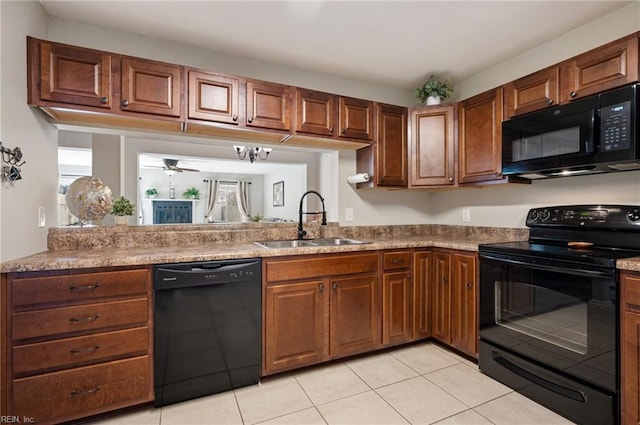 kitchen featuring brown cabinets, light tile patterned floors, light countertops, a sink, and black appliances