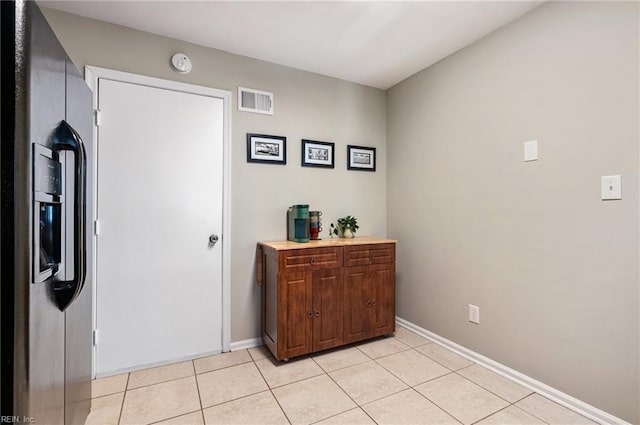 kitchen featuring light tile patterned floors, visible vents, baseboards, light countertops, and black refrigerator with ice dispenser