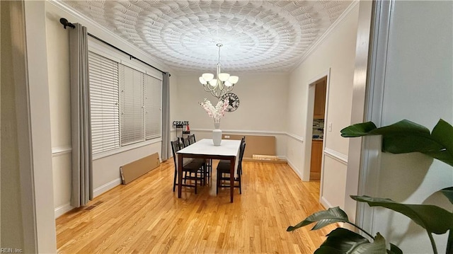 dining area featuring crown molding, visible vents, an inviting chandelier, light wood-type flooring, and baseboards