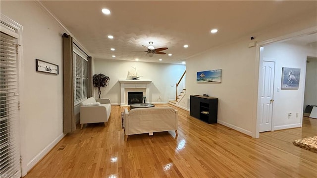 living room with light wood finished floors, ceiling fan, a fireplace, and recessed lighting