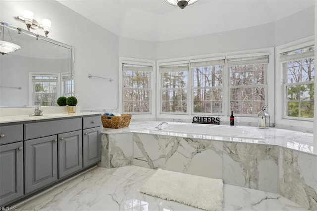 full bathroom featuring marble finish floor, a garden tub, plenty of natural light, and vanity