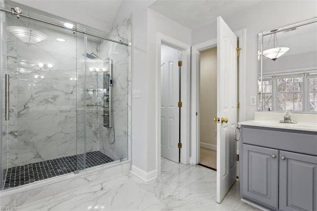 bathroom with marble finish floor, a marble finish shower, baseboards, and vanity