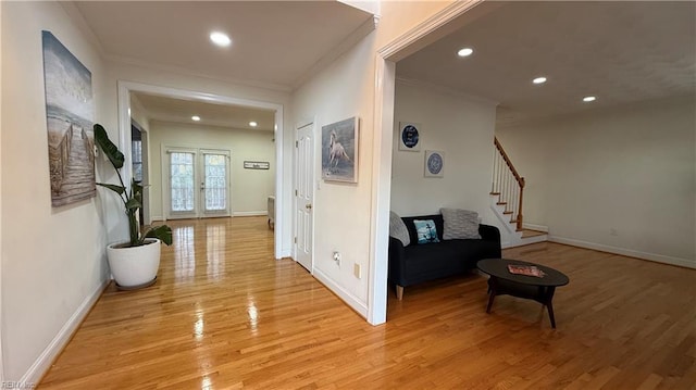 corridor featuring light wood-style floors, stairs, crown molding, and french doors