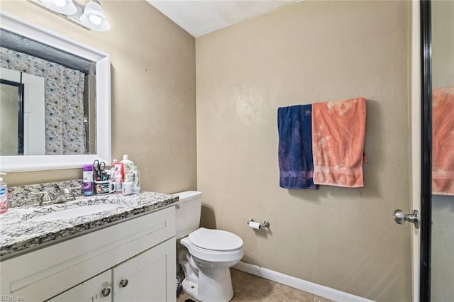 bathroom with toilet, tile patterned floors, baseboards, and vanity