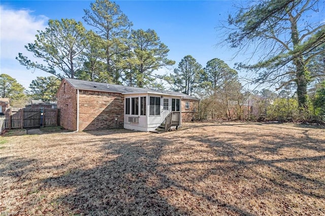 back of house with a sunroom, brick siding, fence, and a gate