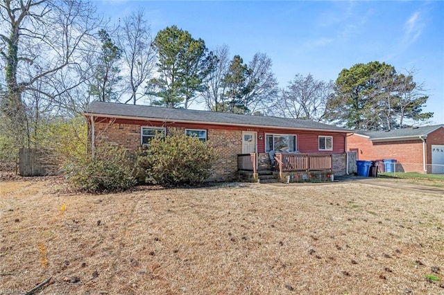 single story home with a wooden deck, a front lawn, and brick siding