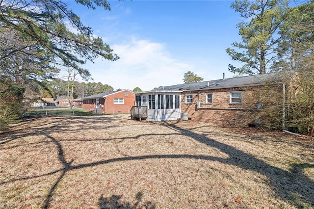 back of property with a sunroom and brick siding