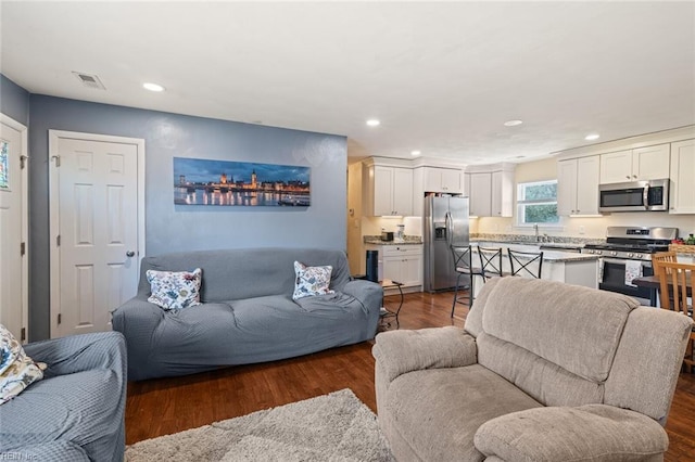 living room with dark wood-style floors, visible vents, and recessed lighting