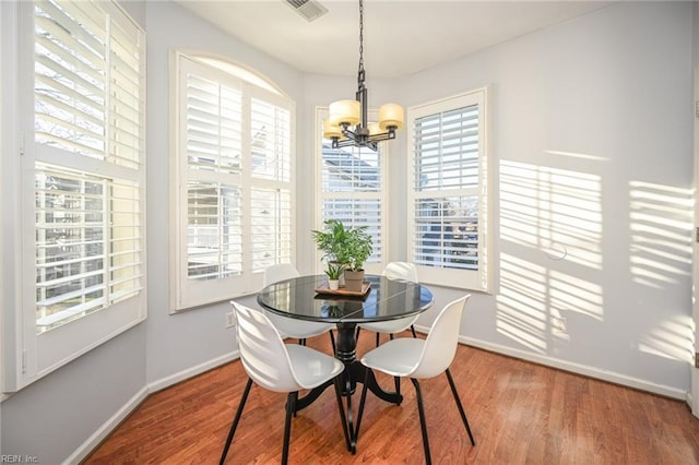 dining space with a notable chandelier, baseboards, visible vents, and wood finished floors