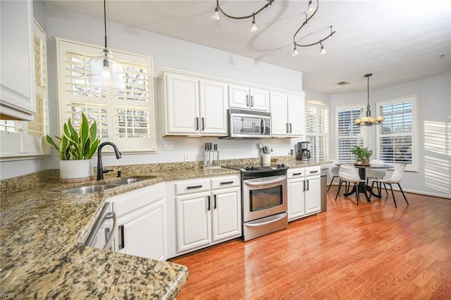 kitchen featuring stainless steel appliances, light wood-type flooring, white cabinetry, and a sink