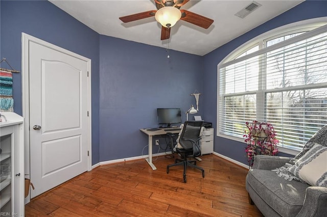 home office featuring a ceiling fan, wood-type flooring, visible vents, and baseboards