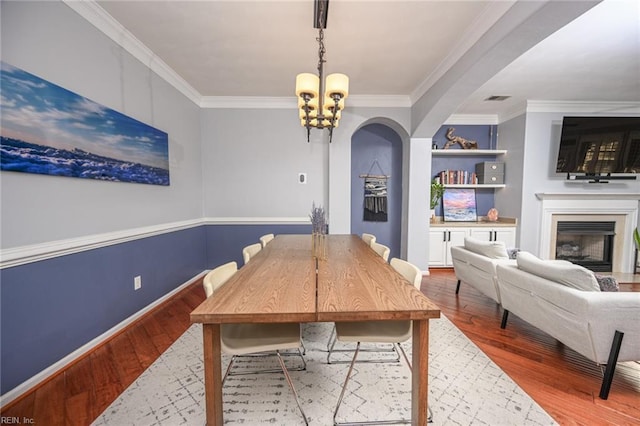 dining space featuring ornamental molding, wood finished floors, and an inviting chandelier