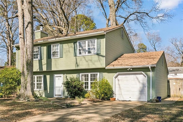 colonial inspired home featuring concrete driveway, a chimney, and an attached garage