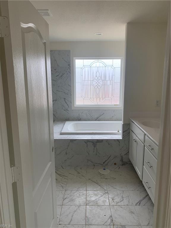 bathroom with a bath, marble finish floor, visible vents, and vanity