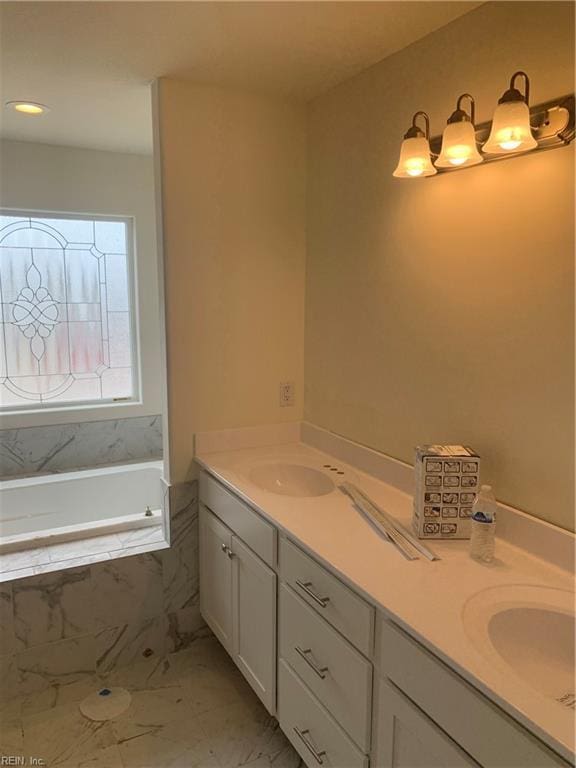 bathroom with a tub to relax in, marble finish floor, a sink, and double vanity