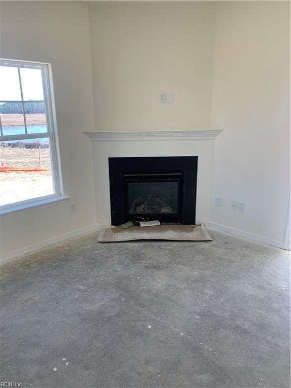 room details featuring concrete flooring, a fireplace, and baseboards