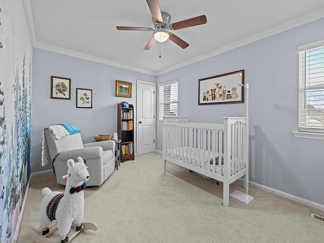 bedroom featuring ceiling fan, carpet floors, baseboards, a crib, and crown molding