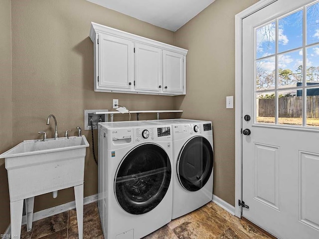 clothes washing area with cabinet space, baseboards, and separate washer and dryer