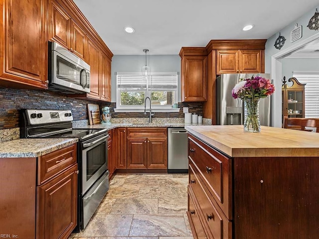 kitchen with wood counters, stone finish floor, appliances with stainless steel finishes, a sink, and backsplash