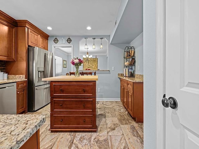 kitchen with brown cabinets, crown molding, stainless steel appliances, a kitchen island, and baseboards