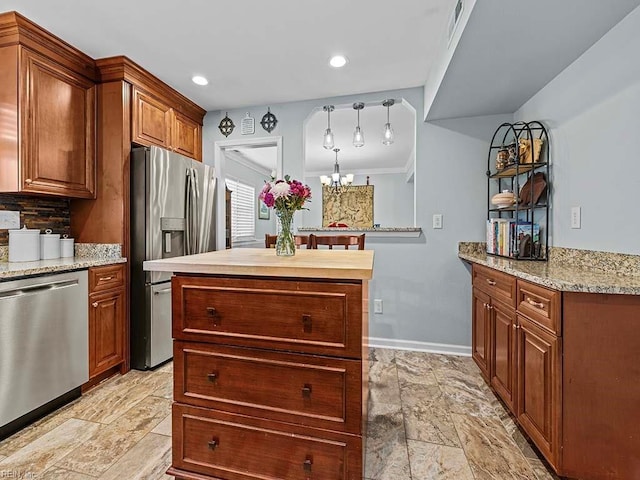 kitchen featuring a chandelier, baseboards, appliances with stainless steel finishes, a center island, and tasteful backsplash