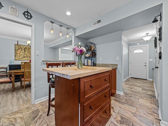 kitchen with baseboards, visible vents, crown molding, and a kitchen breakfast bar