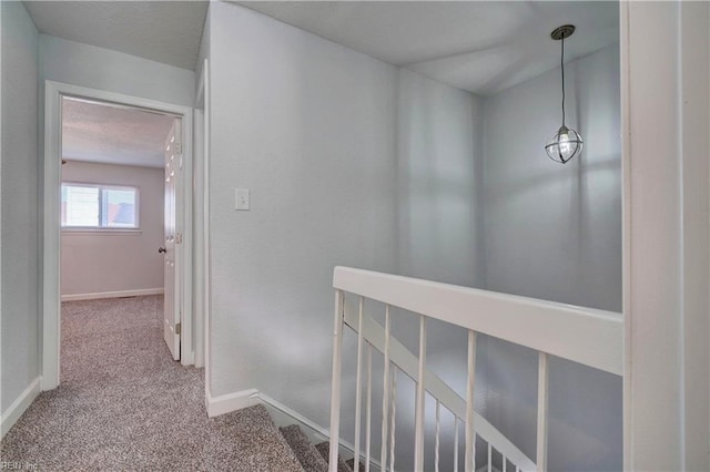 hallway featuring carpet, an upstairs landing, and baseboards