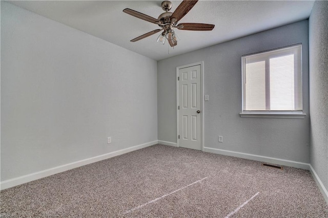 carpeted empty room with visible vents, baseboards, and a ceiling fan