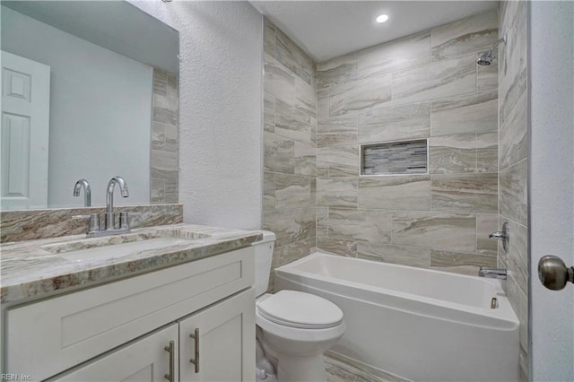 bathroom featuring a textured wall, shower / bath combination, vanity, and toilet