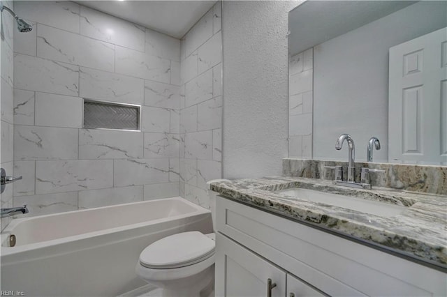 bathroom featuring a textured wall, bathtub / shower combination, vanity, and toilet