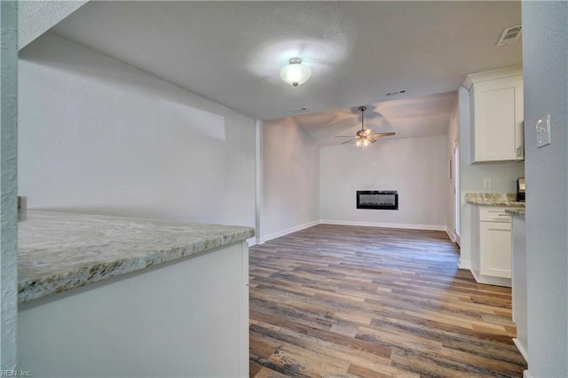 kitchen with ceiling fan, a fireplace, wood finished floors, visible vents, and white cabinets