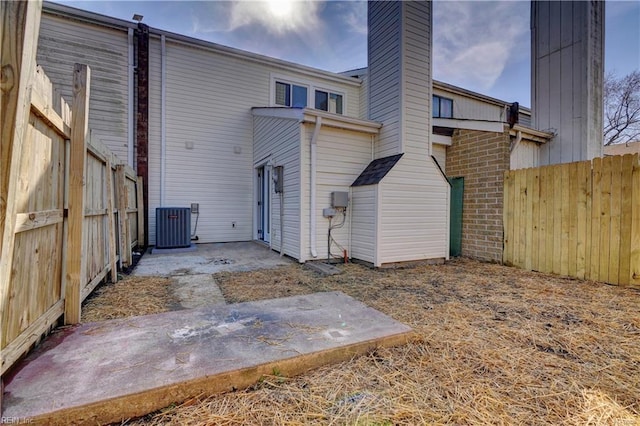 back of house featuring a patio, brick siding, fence, and central air condition unit