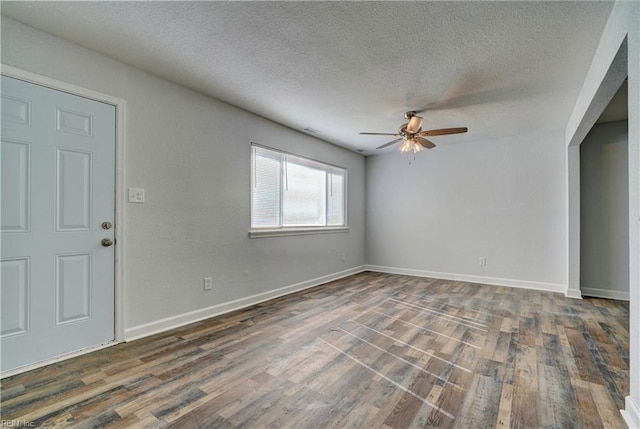 unfurnished room with a textured ceiling, wood finished floors, a ceiling fan, and baseboards