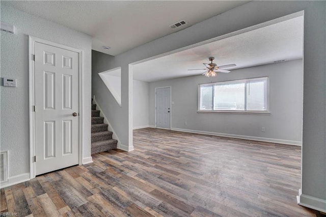 unfurnished room with stairs, wood finished floors, visible vents, and baseboards