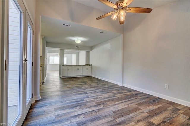 spare room featuring dark wood-style flooring, visible vents, ceiling fan, and baseboards