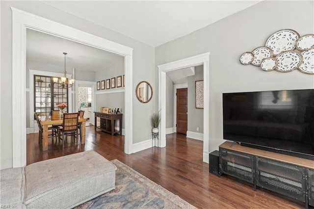 living room with a notable chandelier, baseboards, and wood finished floors