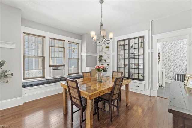 dining area with cooling unit, baseboards, built in features, wood-type flooring, and an inviting chandelier