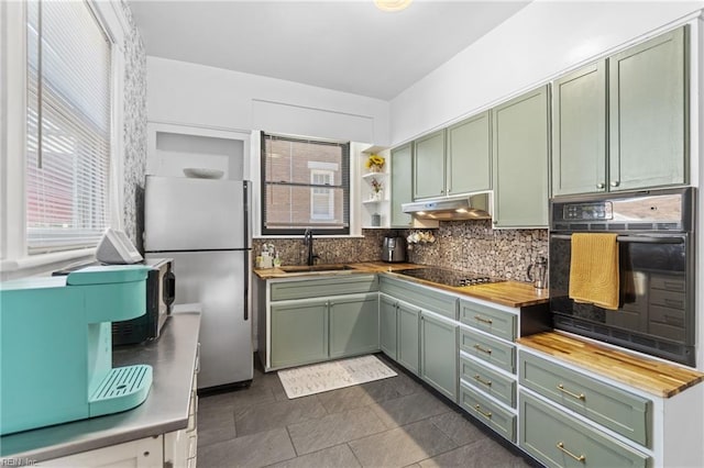 kitchen featuring green cabinets, black appliances, butcher block counters, and a sink